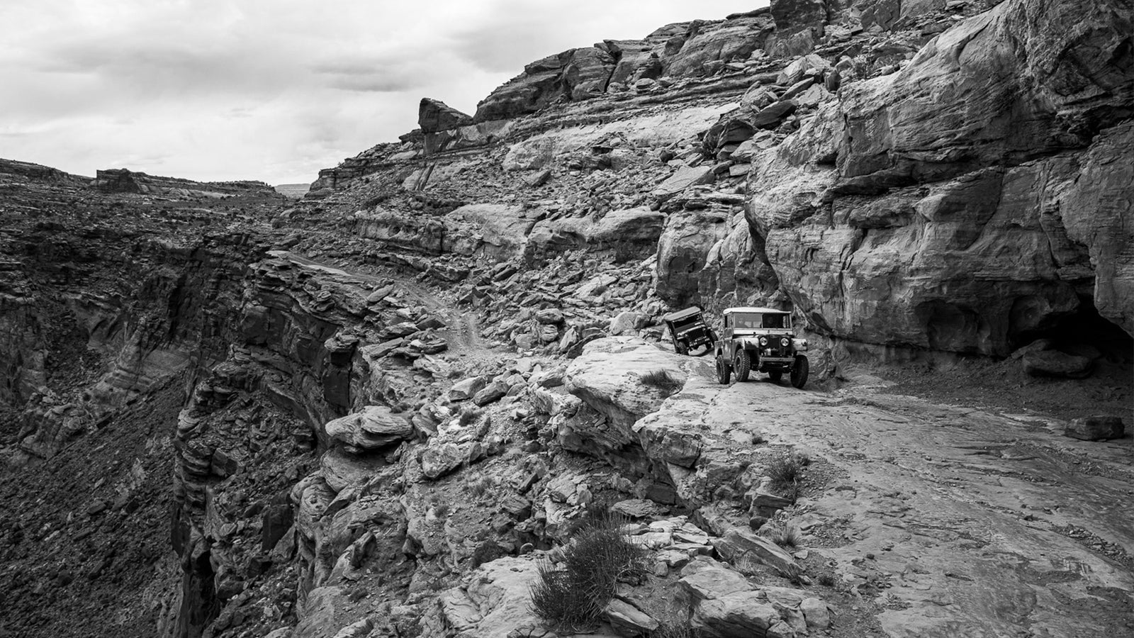 Vintage Land Rover and Jeeps vehicles navigating a rocky ledge trail