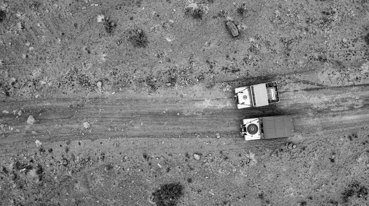 Overhead aerial photo of two Series 1 Land Rover vehicles on a desert trail